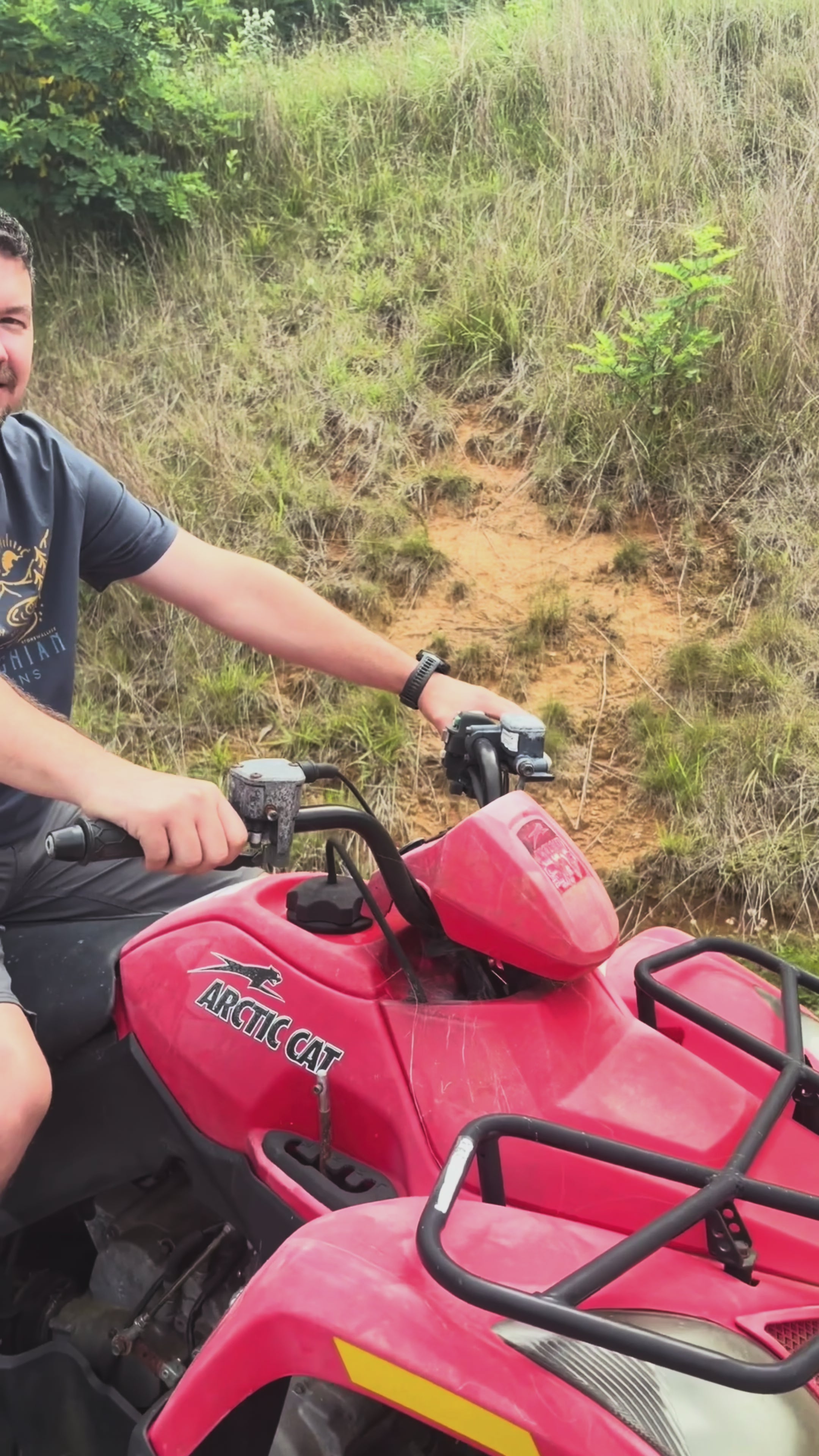 Load video: People wearing different Stonewall828 Appalachia themed tees, a person on a 4Wheeler, a person looking at the Blue Ridge Mountains, A person crossing a fallen log, a person on a tailgate watching the fog over the mountains
